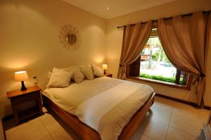 a bedroom with a large bed and a window at Oasis Villas by Fine & Country in Grand Baie