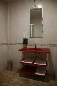 baño con lavabo rojo y espejo en HOSTAL EL POLIGONO, en La Roda