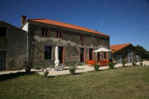 een stenen huis met een tafel en een paraplu bij La convivialité d’un gîte rural pour se retrouver entre amis in LʼAiguillon-sur-Vie