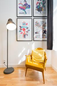 einen gelben Stuhl und eine Lampe in einem Zimmer mit Plakaten in der Unterkunft Leah Studios in Budapest