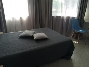 1 dormitorio con cama, silla azul y ventana en La Caroline en Corbie