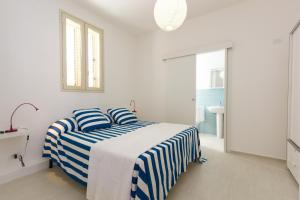 Un dormitorio blanco con una cama con rayas azules y blancas. en Talete, appartamento in centro a 40 mt dalla spiaggia - Pomelia, en Marina di Ragusa