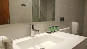 bagno con lavandino bianco e specchio di Hotel Oria a Tolosa