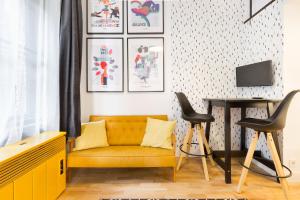 ein Wohnzimmer mit einem gelben Sofa und 2 Hockern in der Unterkunft Leah Studios in Budapest
