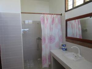 a bathroom with a shower curtain and a sink at Baraka Aquarium Bungalows in Nungwi