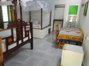 a room with two beds and a bed and a table at Baraka Aquarium Bungalows in Nungwi
