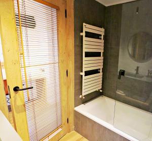 a bathroom with a tub and a glass shower at Hotel Lo Paller in Valencia de Aneu