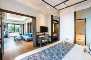 a bedroom with a large bed and a living room at NH Collection Samui Peace Resort in Bophut