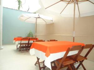 two tables and chairs with orange and white tables and umbrellas at Pousada Clariô in Bertioga