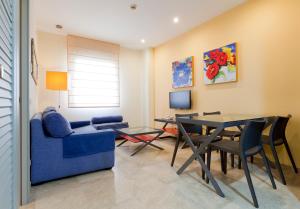 sala de estar con sofá azul y mesa en Apartamentos Vértice Sevilla Aljarafe en Bormujos