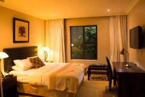 Un dormitorio con una cama y un escritorio y una ventana. en Zawadi House Lodge, en Arusha
