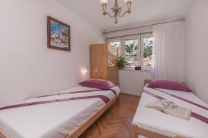 two beds in a small room with a window at Apartment Nansy in Omiš