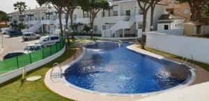 a large blue swimming pool next to a building at Chiclana Costa in Chiclana de la Frontera