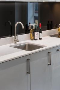 a kitchen sink with two bottles of alcohol on it at Beautiful Chelsea Apartment in Fashion District in London