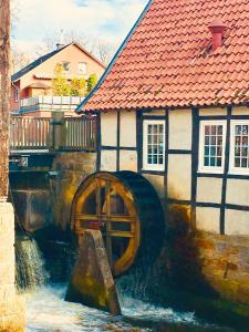a painting of a building next to a water wheel at Das Mühlchen in Ladbergen