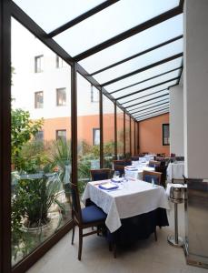restauracja ze stołami i krzesłami oraz dużym oknem w obiekcie Panorama Hotel w Syrakuzach