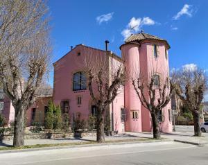 a pink building with a tower next to trees at Torre de la Ferrería in Tona