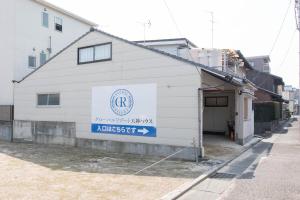un edificio blanco con un cartel en el costado en グローバルリゾート宮島 天神ハウス, en Miyajima
