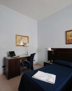 a bedroom with a bed and a desk with a laptop at Panorama Hotel in Syracuse +30 photos