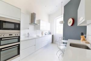 a white kitchen with a sink and a counter at Queens Circus - Montpellier, Central Cheltenham in Cheltenham