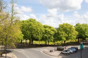 een straat met auto's geparkeerd in een park met bomen bij Queens Circus - Montpellier, Central Cheltenham in Cheltenham