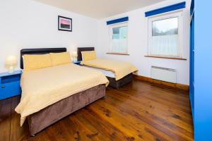 two beds in a room with wooden floors at Dingle Centre Townhouse An Capall Dubh Dingle in Dingle