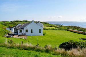 a white house on a hill with a green field at Portbahn, Bruichladdich in Bruichladdich