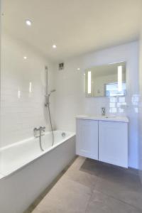 een witte badkamer met een bad en een wastafel bij Sea View in Oostende
