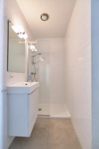 een witte badkamer met een wastafel en een spiegel bij Sea View in Oostende
