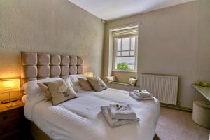 a bedroom with a large white bed with a window at The Commodore Inn in Grange Over Sands