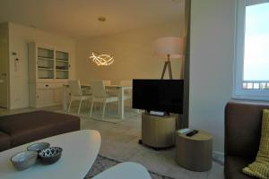 a living room with a couch and a tv and a table at La Promenade Le Normandy 54-201 in Cadzand