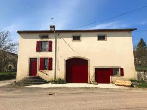 a white building with red doors and stairs next to a street at Countryhouse La Rose in Les Thons
