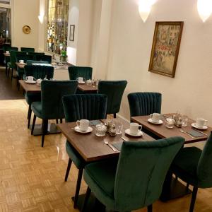 un comedor con mesas de madera y sillas verdes en Hotel Domspitzen en Colonia