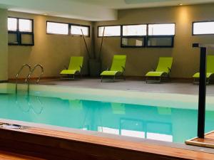 a swimming pool with green chairs in a building at Michelle- Departamentos in Necochea