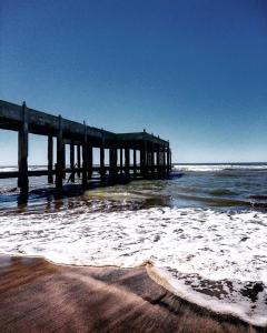 a pier on the beach with the ocean gmaxwell at Michelle- Departamentos in Necochea +10 photos