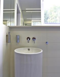 une salle de bains avec un lavabo blanc et un miroir dans l'établissement Apartament Baltica z ogródkiem - w ustronnym miejscu tuż przy plaży, à Rogowo