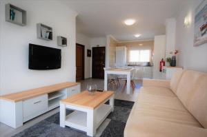 a living room with a couch and a tv on a wall at Apartment MargemSul - Pool - Beach - Free Wifi - Air Con in Albufeira