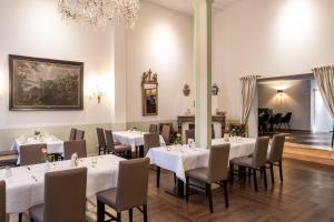 een eetkamer met witte tafels en stoelen en een kroonluchter bij Romantik Hotel Alte Münze in Goslar
