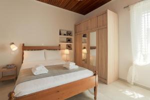 Schlafzimmer mit einem großen Bett mit einem Kopfteil aus Holz in der Unterkunft Splendid Views from a Cozy Cottage with a Garden Terrace in Athen
