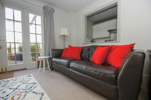 a black leather couch with red pillows in a living room at Arundel Mews - Parking - by Brighton Holiday Lets in Brighton & Hove