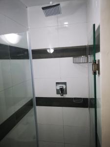 a bathroom with a glass shower door in a room at Jardim das Acácias in Maputo