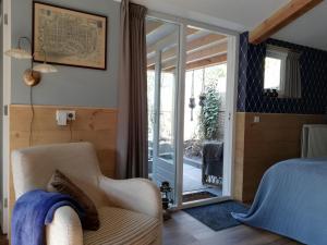 een slaapkamer met een bed en een stoel en een glazen schuifdeur bij Casa Batavia B&B in Lelystad