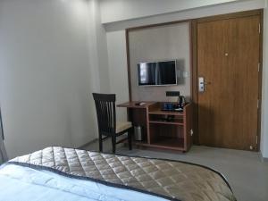 a hotel room with a bed and a desk and a television at Kyriad Hotel Solapur by OTHPL in Solapur