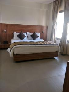 a bedroom with a large bed with a wooden headboard at Kyriad Hotel Solapur by OTHPL in Solapur