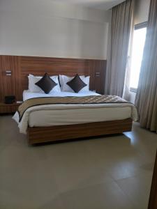 a bedroom with a large bed with a wooden headboard at Kyriad Hotel Solapur by OTHPL in Solapur