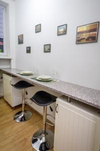 a kitchen with a counter with two chairs and a table at Útulný druhý domov v srdci Žiliny in Žilina