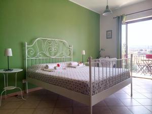 a bedroom with a white bed with a green wall at Good Morning Etna in Bronte +29 photos