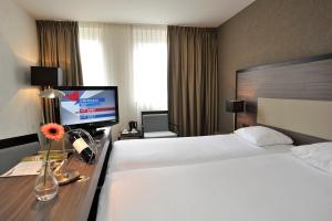 ヴェールトにあるFletcher Hotel-Restaurant Weertのベッド2台、薄型テレビが備わるホテルルームです。