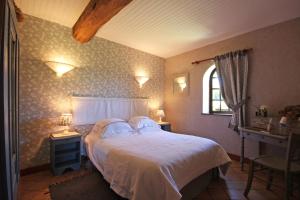 een slaapkamer met een bed, 2 tafels en een raam bij RAND'HÔTES in Les Genettes