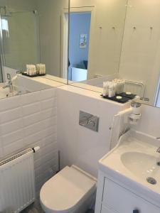 a white bathroom with a toilet and a sink at Willa Błękit Hotel by Dorota Szelągowska in Mielno